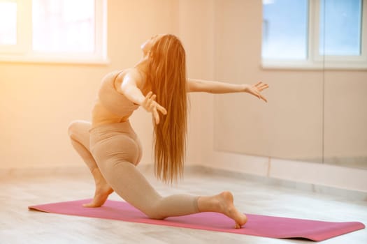 Girl does yoga. Young woman practices asanas on a beige one ton background