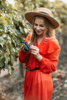 portrait of a happy woman in the summer vineyards at sunset. woman in a hat and smiling