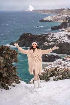 Woman snow sea. Amidst a wintry backdrop, a woman in a beige faux fur coat gleefully engages in a snowball fight, adding joy to the serene seascape