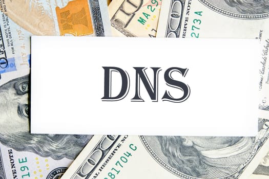 DNS. Domain Name System word writing on a white card against the background of banknotes