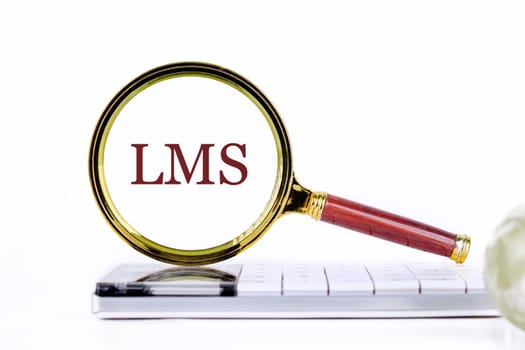 Abbreviation of Learning management system, Word LMS writing through a magnifying glass on a calculator on a light background. Business development concept