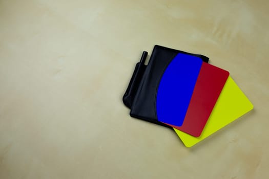 Black notebook of football referee with a pencil for notes and red, yellow, blue cards in a pocket on table, new rules in football, blue color of card