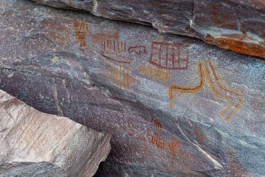 Colorful ancient petroglyphs with symbolic imagery etched on stone captured in a detailed photograph.
