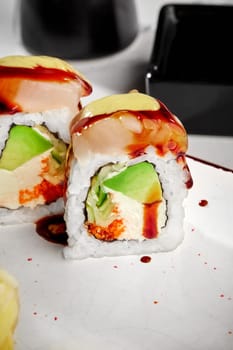 Closeup of appetizing sushi rolls with sea scallop, cream cheese, masago roe and avocado seasoned with spicy mayo an unagi sauce served on plate. Popular Japanese snack