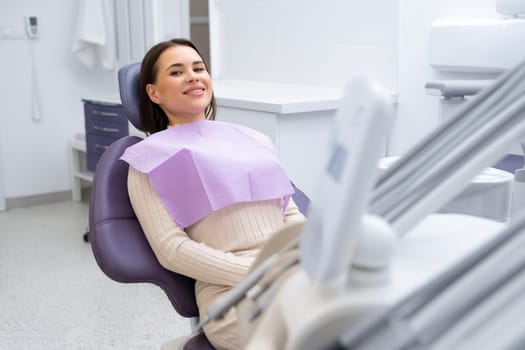 A smiling woman sitting in a dental chair and waiting for a checkup in the clinic.