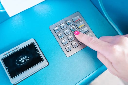 A female hand is using a communication device to press a button on an ATM machine, with a gesture of her finger. The office equipment has an electric blue font, enhancing the gadgets appearance