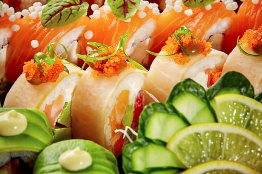Vibrant close-up of assorted sushi rolls featuring salmon, avocado, and mamenori, garnished with tobiko, cucumber and lime slices. Popular Asian style snack