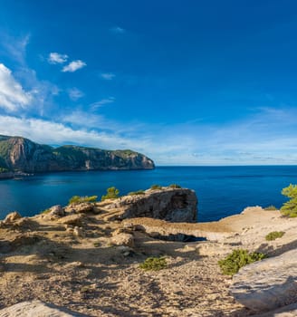 Breathtaking cliff panorama beside a vibrant blue sea under sunny skies.