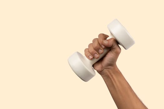 Black male hand holding a white dumbell isolated, light beige background. High quality photo