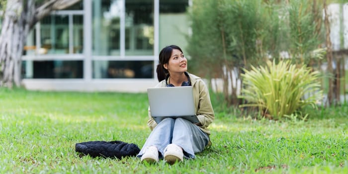 Young Asian student sitting and using laptop at university before class room. education, back to school concept.