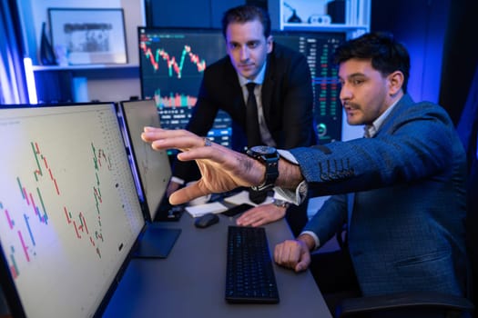 Stock exchange traders looking on high profit chart investment in panorama view, analyzing on monitor at night. Concept of discussing financial technology growth in neon light at workplace. Sellable.