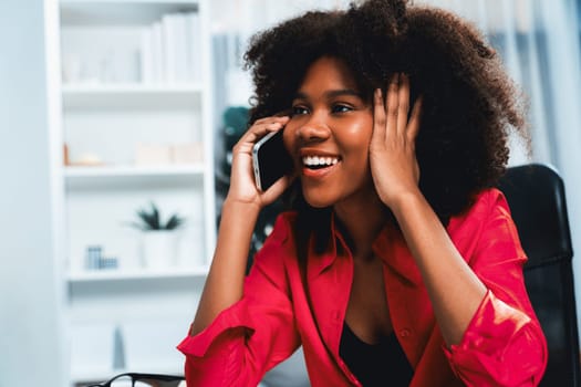 African woman talking with coworker or friend on the phone and looking at the screen with happy face. Achievement for promoting job position in the company with the good news life. Tastemaker.