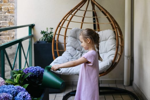 Girl watering hydrangeas on the balcony