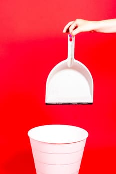 Woman throwing crumpled a paper from scoop into rubbish bin on red background