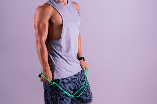 Young man exercising with skipping rope and looking at the camera isolated on grey background