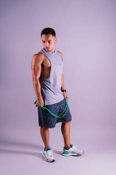 Young man exercising with skipping rope and looking at the camera isolated on grey background