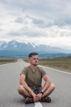 A young man sitting on the road in the Chuysky Tract area. Altai Republic, Russia.