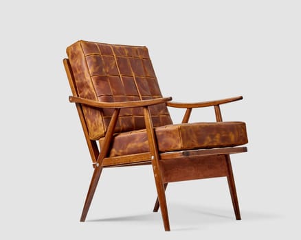 Vintage wooden armchair with soft brown patchwork leather cushions against white background. Artisanal furniture concept