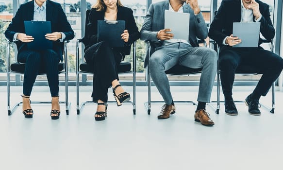 Businesswomen and businessmen holding resume CV folder while waiting on chairs in office for job interview. Corporate business and human resources concept. uds