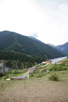 Traditional Kazakhstan yurt camp in scenic mountain valley near river. Cozy felt and wood yurts offer local hospitality amidst snow-capped peaks.