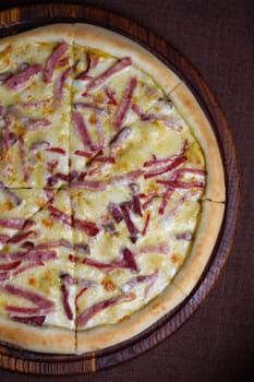 Savory pizza topped with gooey melted cheese and sliced ham, shot in a well-lit setting with a blurred background, creating an appetizing image.