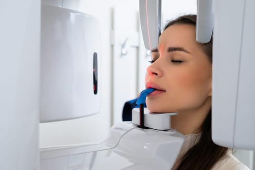 Portrait young woman having panoramic digital X ray of her teeth in dentist office