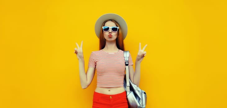 Stylish young woman posing in summer straw hat with backpack on vivid yellow studio background
