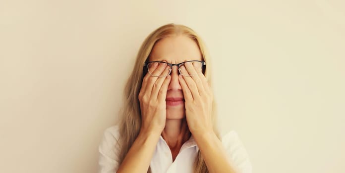 Tired overworked woman employee rubbing her eyes suffering from eye strain, dry eye syndrome or headaches