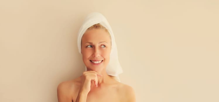 Natural beauty portrait of middle-aged woman thinks looking away with white bath towel on head after shower in morning