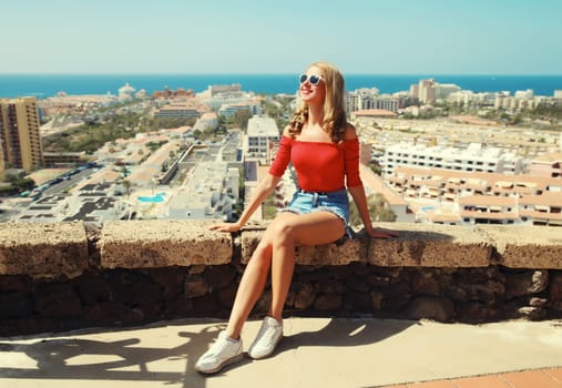 Summer vacation, beautiful young woman tourist on top of the mountain looking around the city in Tenerife, Canary Islands, Spain. Aerial top view.