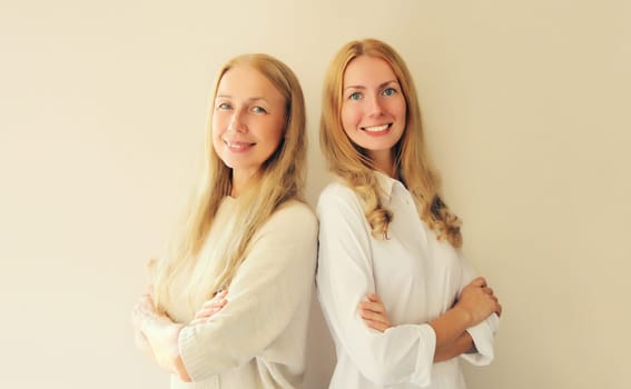 Portrait of happy smiling caucasian middle aged mother or sister and adult daughter together on studio background