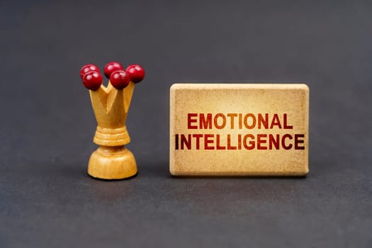 Leader concept. On a black surface there is a chess piece and a wooden block with the inscription - Emotional intelligence