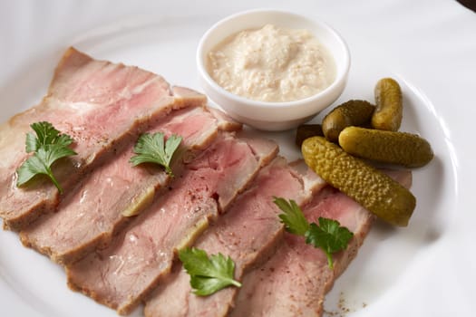 Close-up of smoked meat with salty sauce and pickles