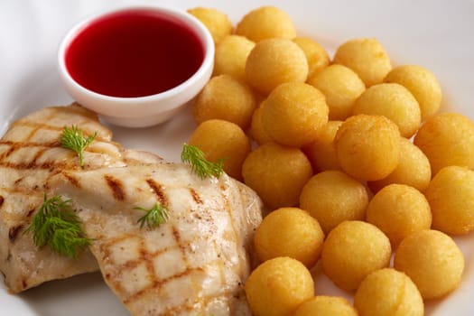 Close-up of grilled meat, cheese balls and cranberry sauce