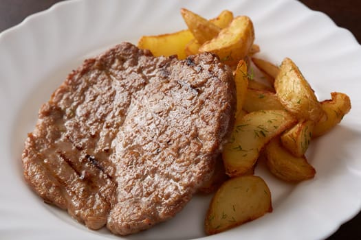 Image of delicious pork chop and potato wedges, close-up