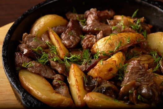 Potato wedges fried with meat and mushrooms, close-up