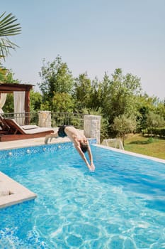 Young man dives with his arms forward into the pool near the sun loungers. High quality photo