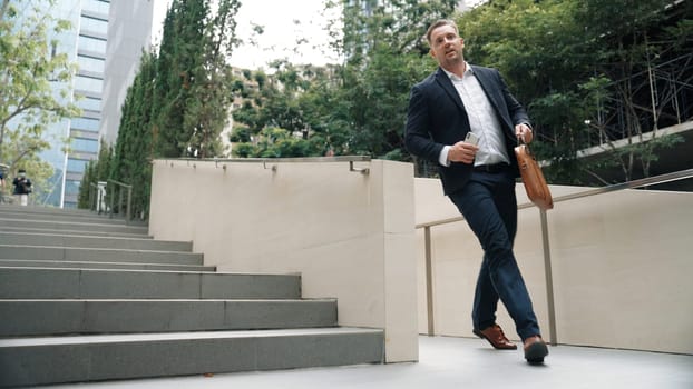 Worried smart business man running up stairs with hurry at green eco city. Anxious project manager rushing for not being late in important meeting while going to workplace at park. Lifestyle. Urbane.