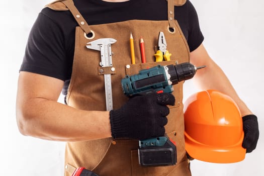 Craftsman in apron holding drill and helmet