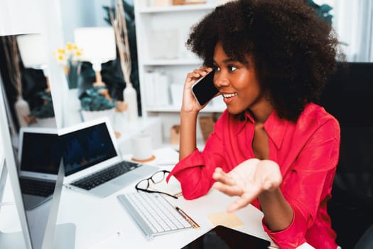 African woman talking with coworker or friend on the phone and looking at the screen with happy face. Achievement for promoting job position in the company with the good news life. Tastemaker.