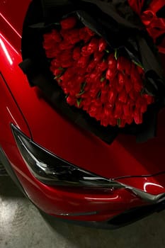 A large bouquet of bright red tulips on a red car. High quality photo