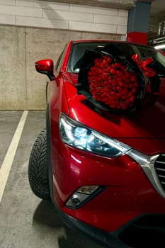 A large bouquet of bright red tulips on a red car. High quality photo