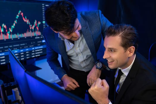 Successful two stock exchange traders raising fist up for digital currency achievement focusing on dynamic data background. Business partners earning high profit analyzed by market graph. Sellable.