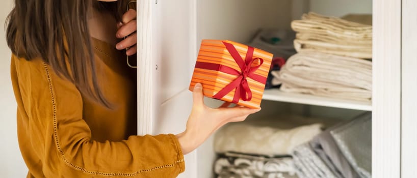 A funny young girl is in a hurry to hide a gift for a loved one, husband, children, friends and parents, a woman wants to make a surprise and hides the gift in the closet during holidays.
