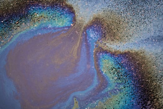 Oil stain on Asphalt in a puddle, color Gasoline fuel spots on Asphalt Road as Texture or Background.