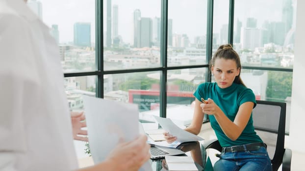 Professional female investor listening businessman present start up project statistic. Back view of businessman shows graph while manager using laptop analysis data at cityscape view. Tracery