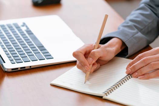 Businesswoman taking note while working on business on workspace table. Young college student study writing or brainstorming strategic plan in office workplace for business success. Blithe