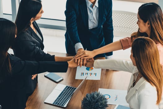 Businesswomen joining hands in group meeting at modern office room showing teamwork, support and unity in work and business. Female power and femininity concept. uds