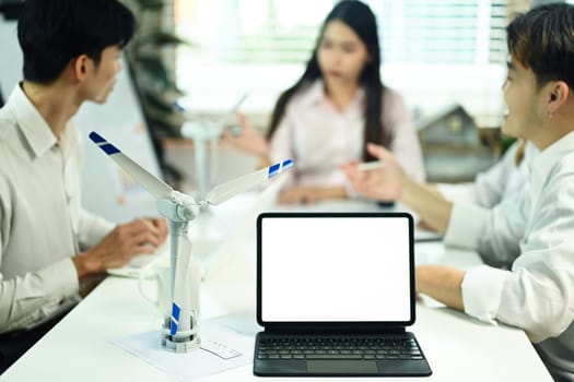 Wind turbine model and digital tablet on a meeting table. Alternative green energy development concept.