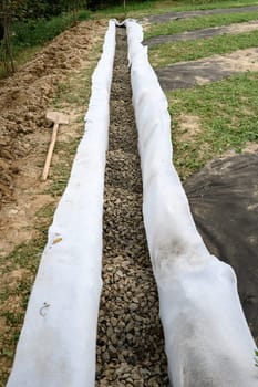 The drainage trench is covered with geotextile and filled with crushed stone to drain ground water from the site and adjacent territory